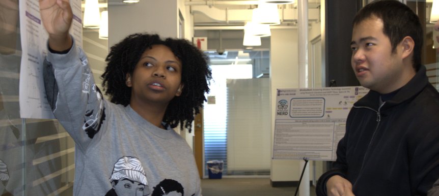 Students discussing a research poster at the NYU WIRELESS Open House